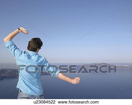 Stock Image - Man stretching his arms, sea view. Fotosearch