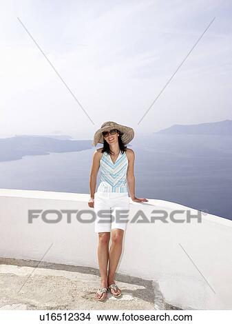 Picture - Woman leaning on a low wall, sea view. Fotosearch