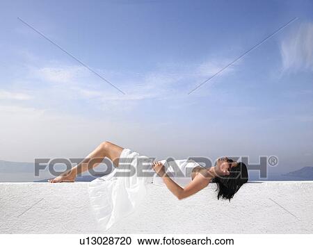 Stock Image - Woman resting on a white wall. Fotosearch