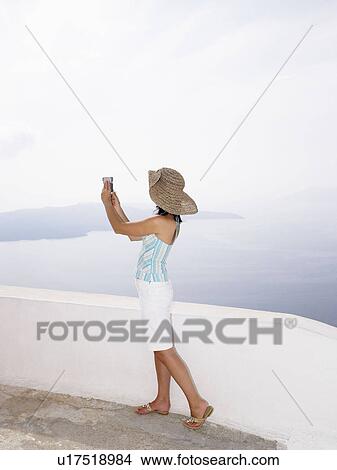 Picture - Woman taking a picture of the sea. Fotosearch