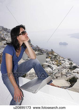 Woman with laptop sitting on a low wall View Large Photo Image Stock Image - Woman with laptop sitting on a low wall. Fotosearch