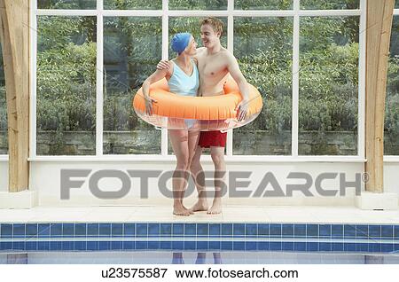 Stock Photo - Couple standing in rubber ring by pool.. Fotosearch