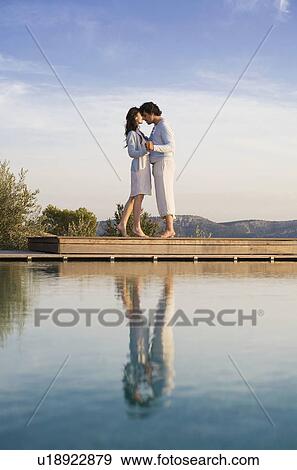 Loving couple face to face hold hands on wood deck by water and blue sky. View Large Photo Image Stock Photo - Loving couple face to face hold hands on wood deck by water and blue sky.. Fotosearch