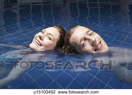 Stock Image - Man and woman floating in a pool.. Fotosearch