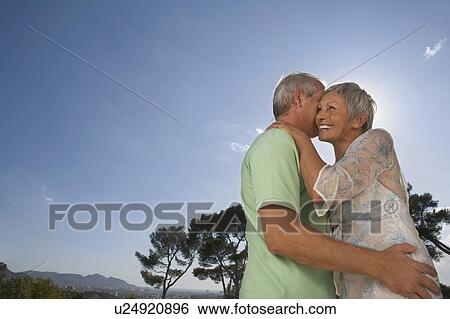 Stock Photograph - Older couple hugging on terrace.. Fotosearch