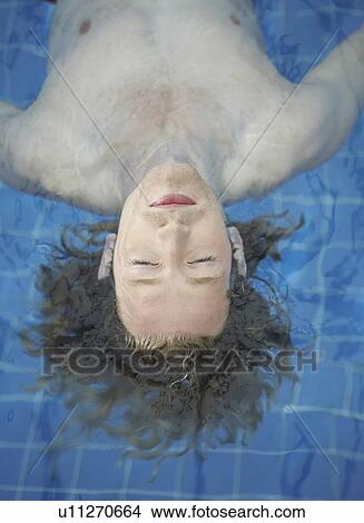 Picture - Portrait of a man floating in a pool.. Fotosearch