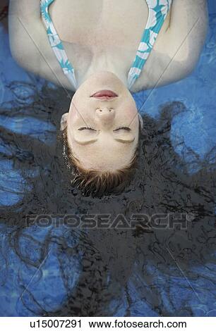 Stock Image - Portrait of a woman floating in a pool.. Fotosearch