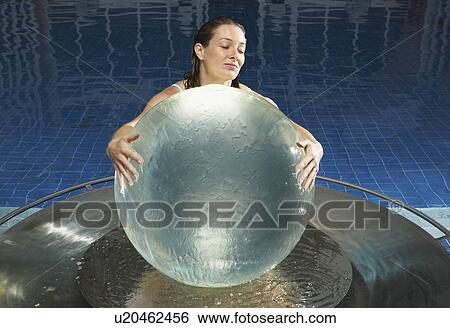 Stock Photograph - Woman with water globe in pool.. Fotosearch