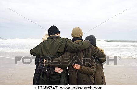 Stock Photo - Group of friends hugging on beach. Fotosearch