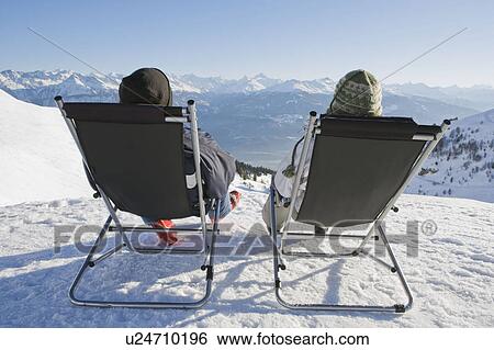 Man, woman relax on deck chairs in snow View Large Photo Image Stock Photograph - Man, woman relax on deck chairs in snow. Fotosearch