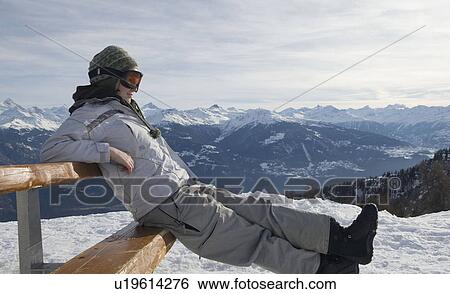 Stock Photograph - Snowboarder sitting on bench . Fotosearch