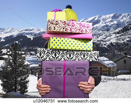 Stock Image - Young man holding pile of presents. Fotosearch