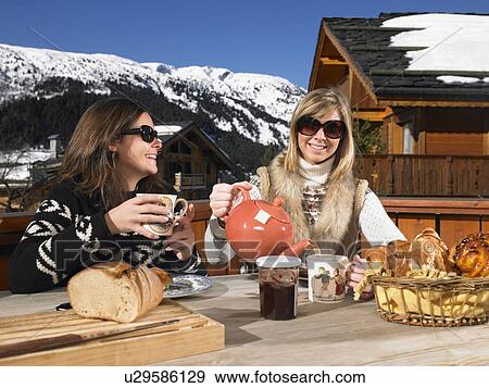 Stock Photo - Young women having breakfast on terrace. Fotosearch