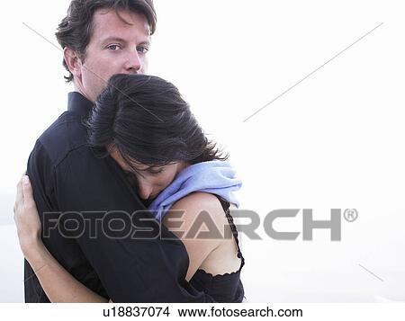 Picture - Couple hugging, man looking at camera. Fotosearch