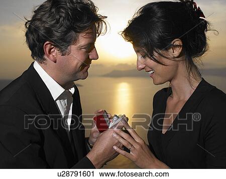 Stock Image - Man proposing to woman, sunset. Fotosearch