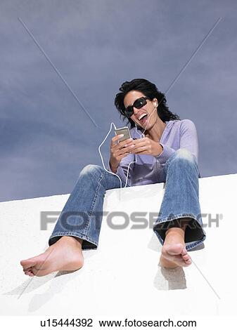 Stock Image - Woman listening to music with ear phones. Fotosearch