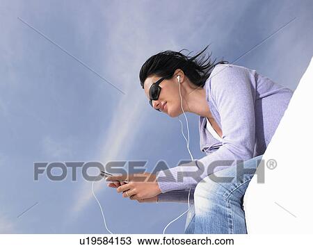 Stock Image - Woman listening to music with ear phones. Fotosearch