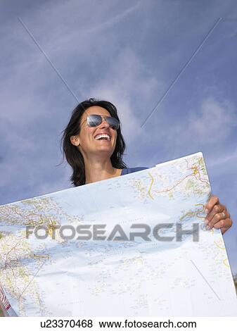 Stock Photo - Woman looking at a map, laughing. Fotosearch