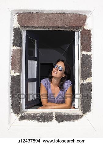 Woman looking through window, smiling View Large Photo Image Picture - Woman looking through window, smiling. Fotosearch