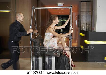 Bellboy pushing woman on luggage trolley View Large Photo Image Picture - Bellboy pushing woman on luggage trolley. Fotosearch