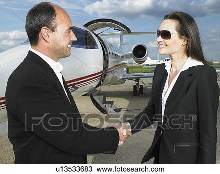 Businessman and businesswoman shaking hands in front of private jet. View Large Photo Image Stock Image - Businessman and businesswoman shaking hands in front of private jet.. Fotosearch