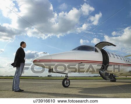 Businessman facing private jet on tarmac. View Large Photo Image Stock Image - Businessman facing private jet on tarmac.. Fotosearch
