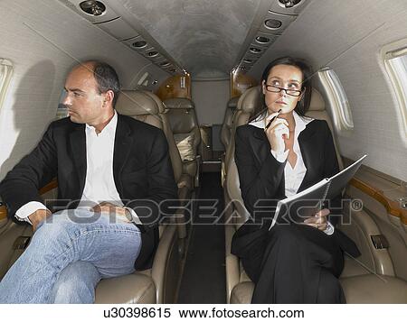 Businesswoman and businessman seated inside a private jet. View Large Photo Image Stock Photography - Businesswoman and businessman seated inside a private jet.. Fotosearch