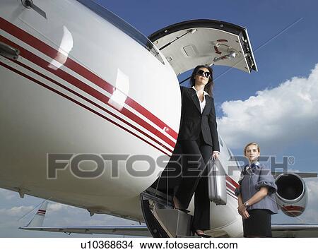 Businesswoman exiting private jet next to flight attendant. View Large Photo Image Picture - Businesswoman exiting private jet next to flight attendant.. Fotosearch