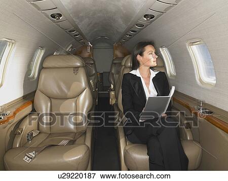 Businesswomen sitting in private jet doing work. View Large Photo Image Stock Photo - Businesswomen sitting in private jet doing work.. Fotosearch