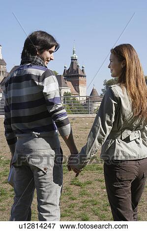 Couple holding hands in a park smiling. View Large Photo Image Stock Photo - Couple holding hands in a park smiling.. Fotosearch