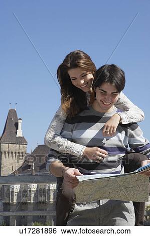 Couple looking at a map outdoors smiling. View Large Photo Image Stock Photograph - Couple looking at a map outdoors smiling.. Fotosearch
