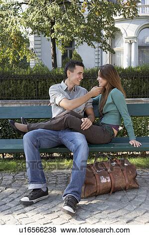 Stock Photo - Couple sitting on a bench smiling.. Fotosearch