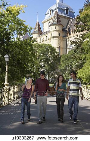 Stock Photo - Four friends walking on a bridge smiling.. Fotosearch