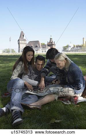 Four people in a park looking at a map smiling. View Large Photo Image Stock Image - Four people in a park looking at a map smiling.. Fotosearch