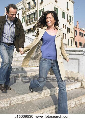 Stock Image - Italy, Venice, couple running down steps. Fotosearch