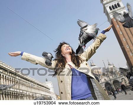 Italy, Venice, woman holding arms outstretched to pigeons View Large Photo Image Picture - Italy, Venice, woman holding arms outstretched to pigeons. Fotosearch