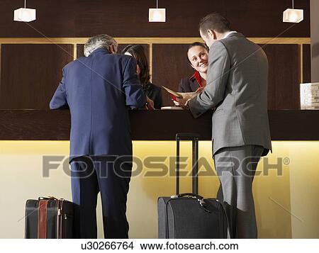 Two businessmen standing at hotel reception View Large Photo Image Picture - Two businessmen standing at hotel reception. Fotosearch
