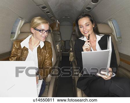 Two women having a discussion on a private jet. View Large Photo Image Stock Image - Two women having a discussion on a private jet.. Fotosearch
