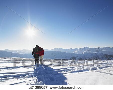 Stock Photo - Couple walking in snow on mountain top. Fotosearch