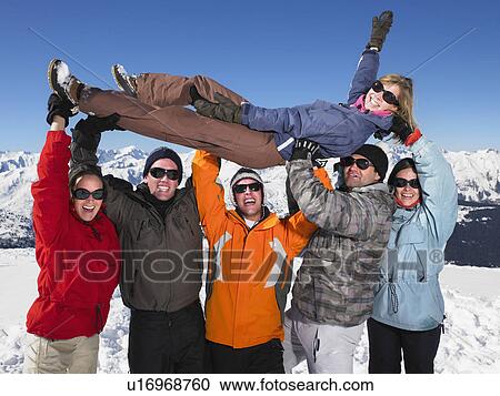 Stock Image - Group holding young woman in air. Fotosearch