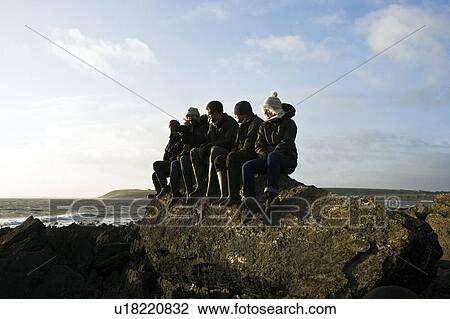 Stock Image - Group of Friends sitting on rock. Fotosearch