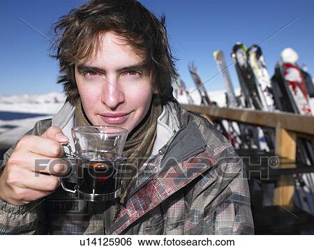 Stock Photograph - Man drinking hot drink at ski resort. Fotosearch