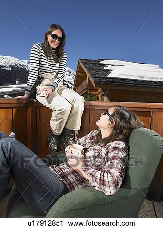 Stock Image - Young women chatting on terrace. Fotosearch