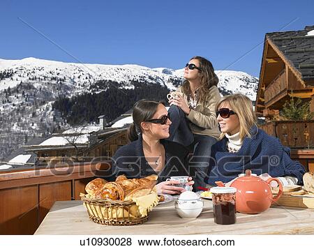 Stock Photo - Young women having breakfast on terrace. Fotosearch