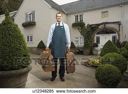 Stock Photography - Man carrying luggage outside hotel.. Fotosearch