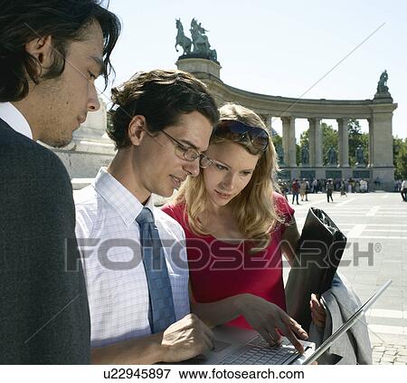 Stock Photo - Three businesspeople looking at laptop.. Fotosearch