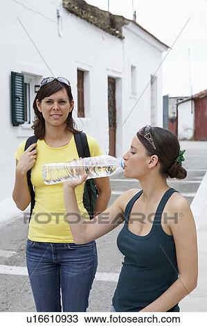 Stock Image - Two young women taking a break in old city square.. Fotosearch