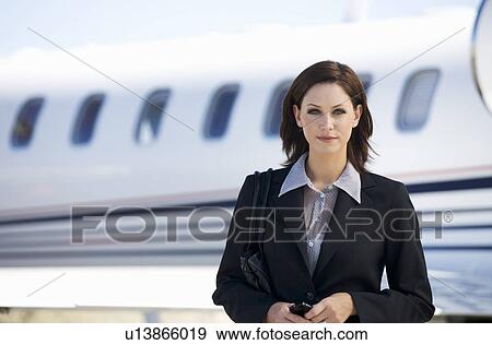 Stock Photo - A business woman standing by a plane. Fotosearch
