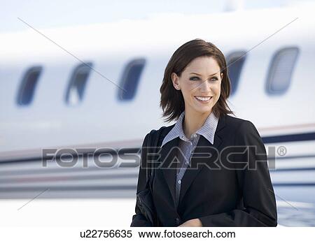 Stock Photography - A business woman standing by a plane. Fotosearch