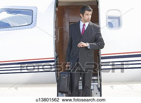 Stock Image - A businessman leaving a plane. Fotosearch